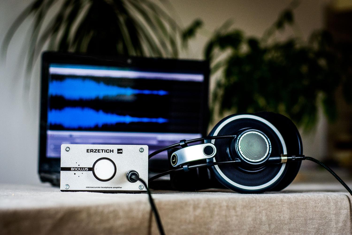 Equipo de audio con amplificador, auriculares y un ordenador mostrando una onda sonora, representando la parte técnica y de cálculo.