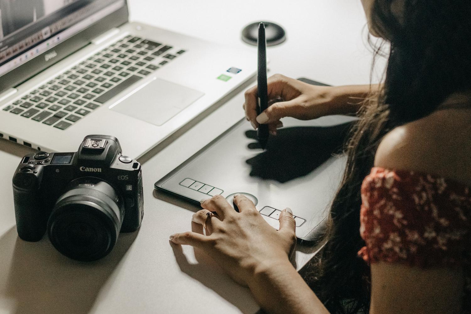 Mujer diseñando arte digital con una tableta y portátil, enfocada en el aprendizaje de herramientas de animación.