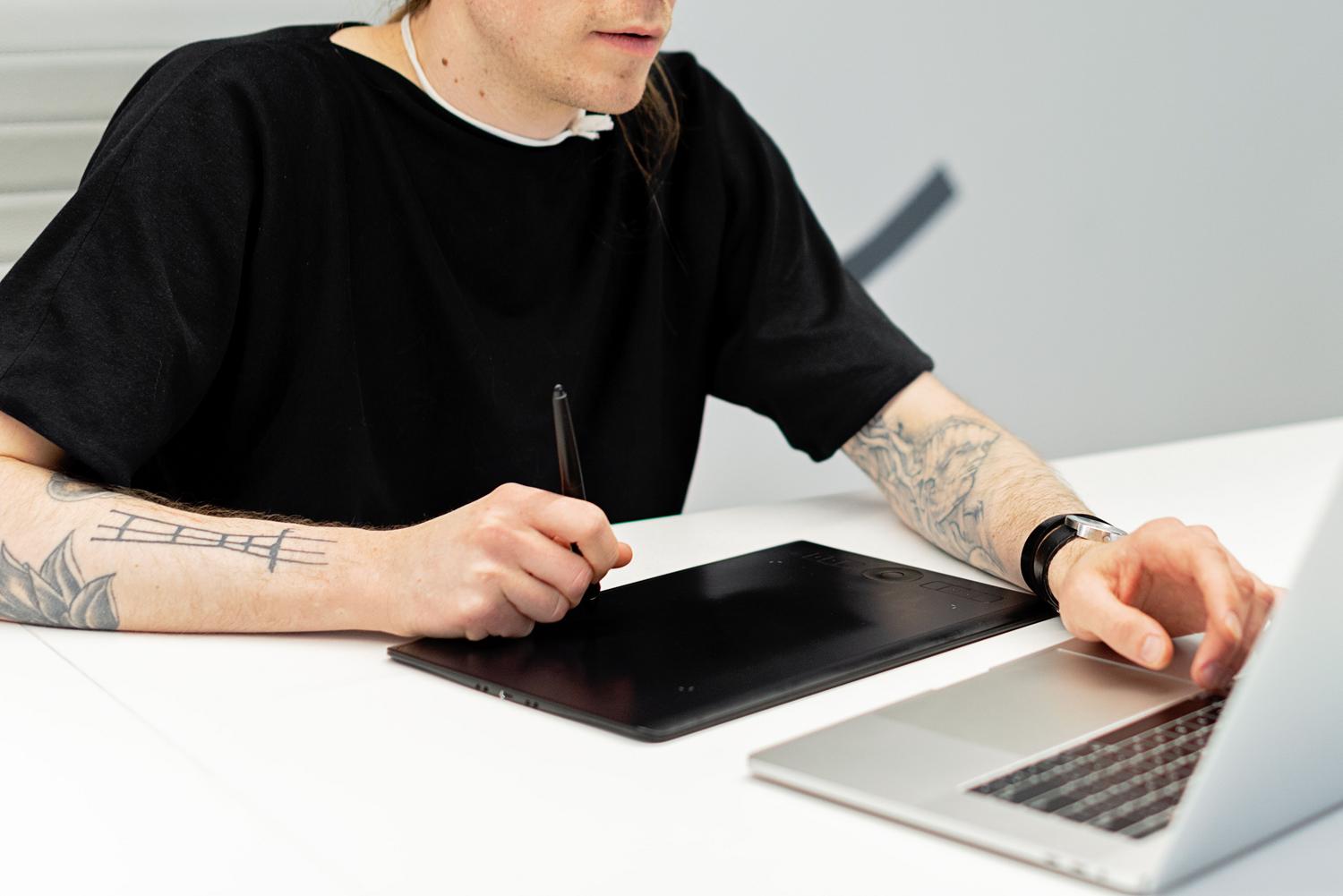 Artista digital utilizando una tableta gráfica y un ordenador portátil para crear animaciones.