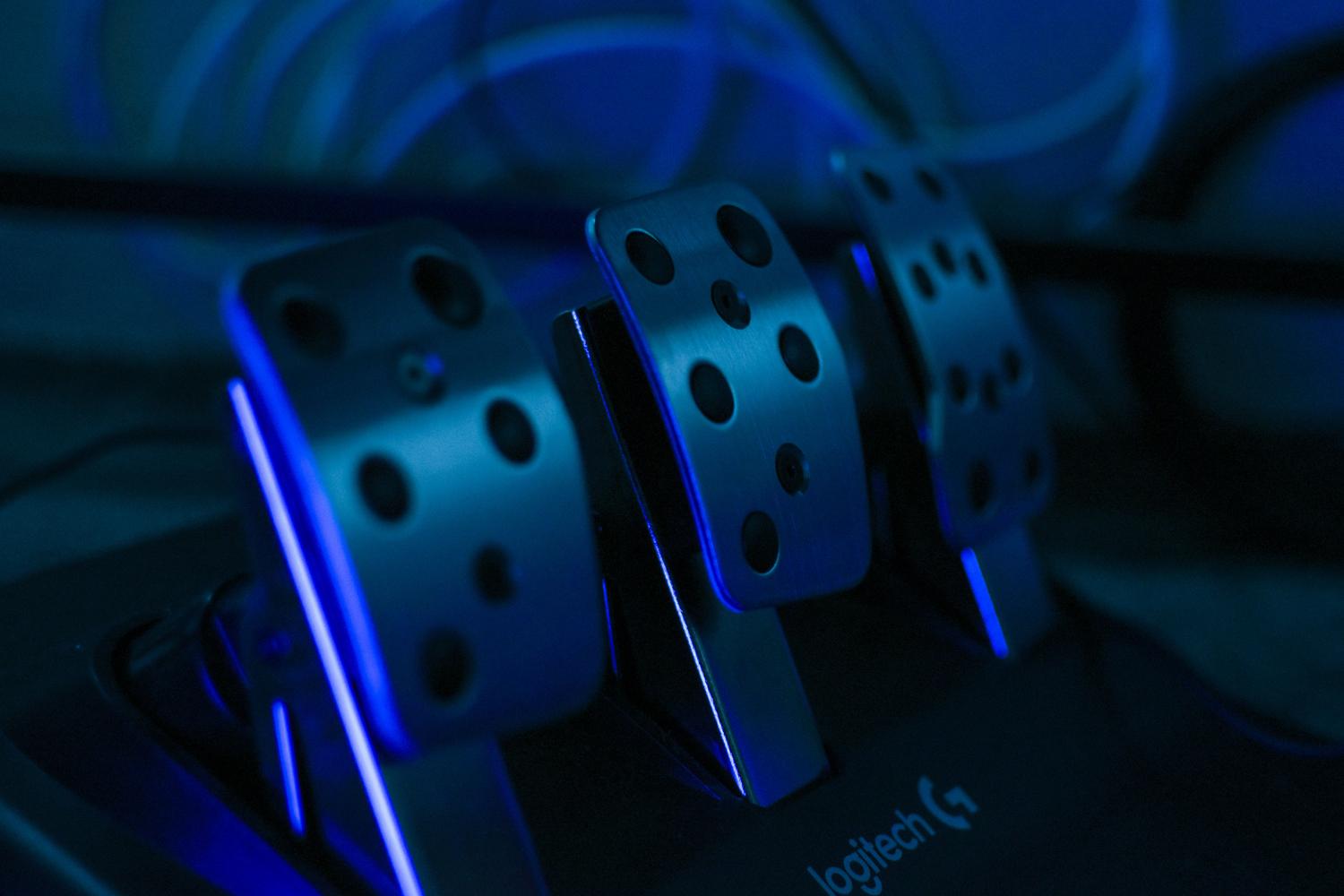 Detalle de los pedales de un simulador de carreras iluminados con luces LED azules
