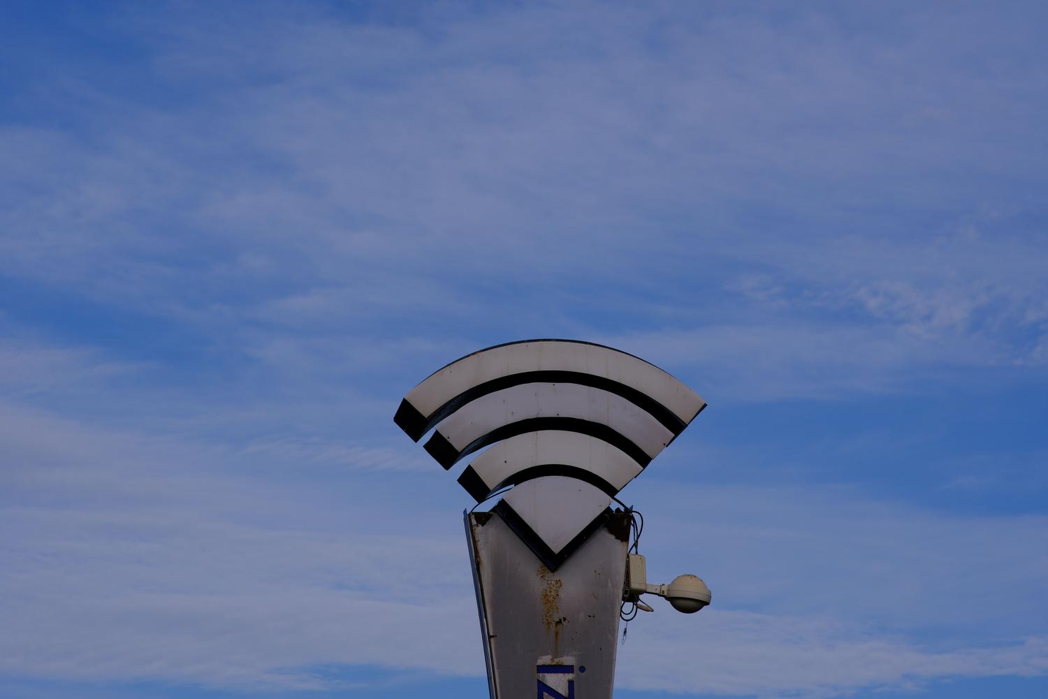 Escultura metálica del símbolo de WiFi sobre un cielo azul, evocando el concepto de conectividad inalámbrica y la naturaleza intangible e inestable de las señales Wi-Fi.