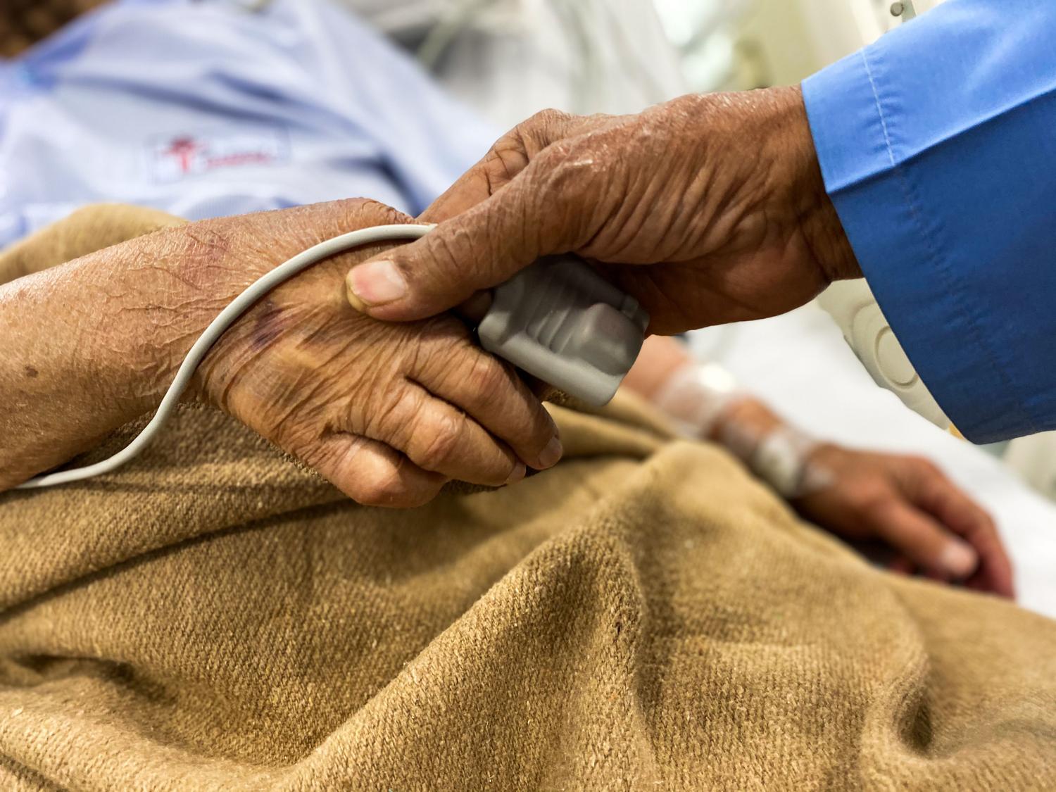 Dos personas mayores tomadas de la mano en un entorno hospitalario, representando el apoyo emocional y el cuidado familiar.