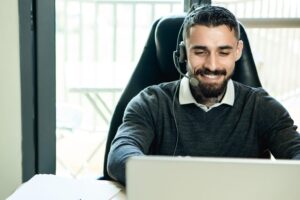 Agente de soporte técnico amable con auriculares trabajando en una oficina moderna