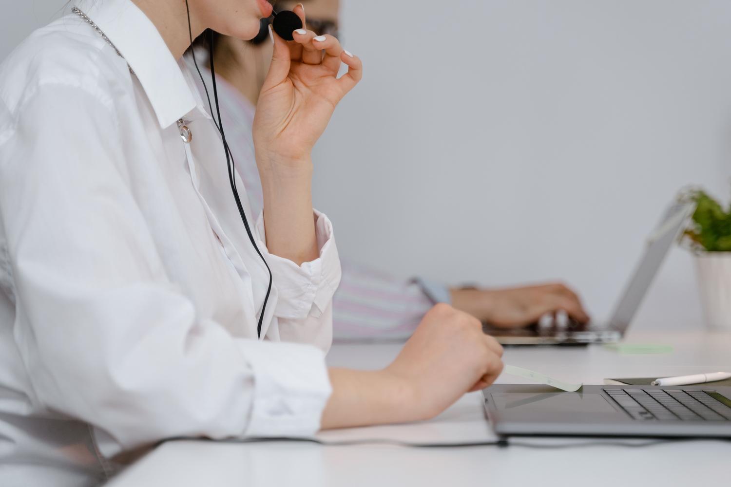 Profesional de soporte técnico concentrada trabajando con portátil y auriculares