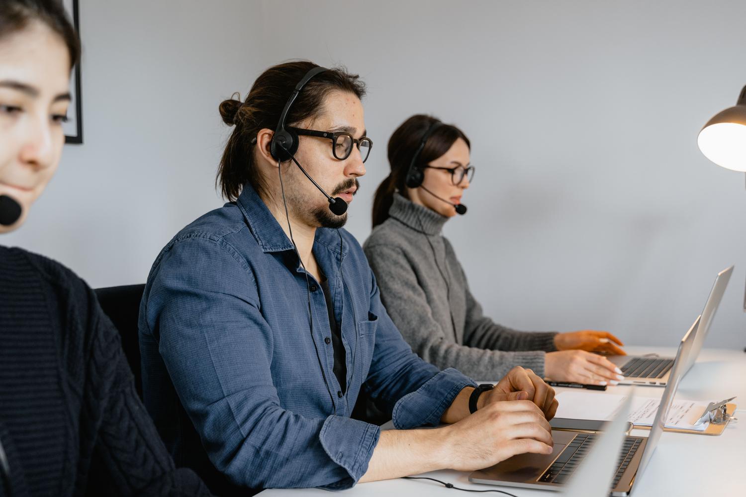 Equipo de atención al cliente en un centro de llamadas utilizando ordenadores portátiles y cascos