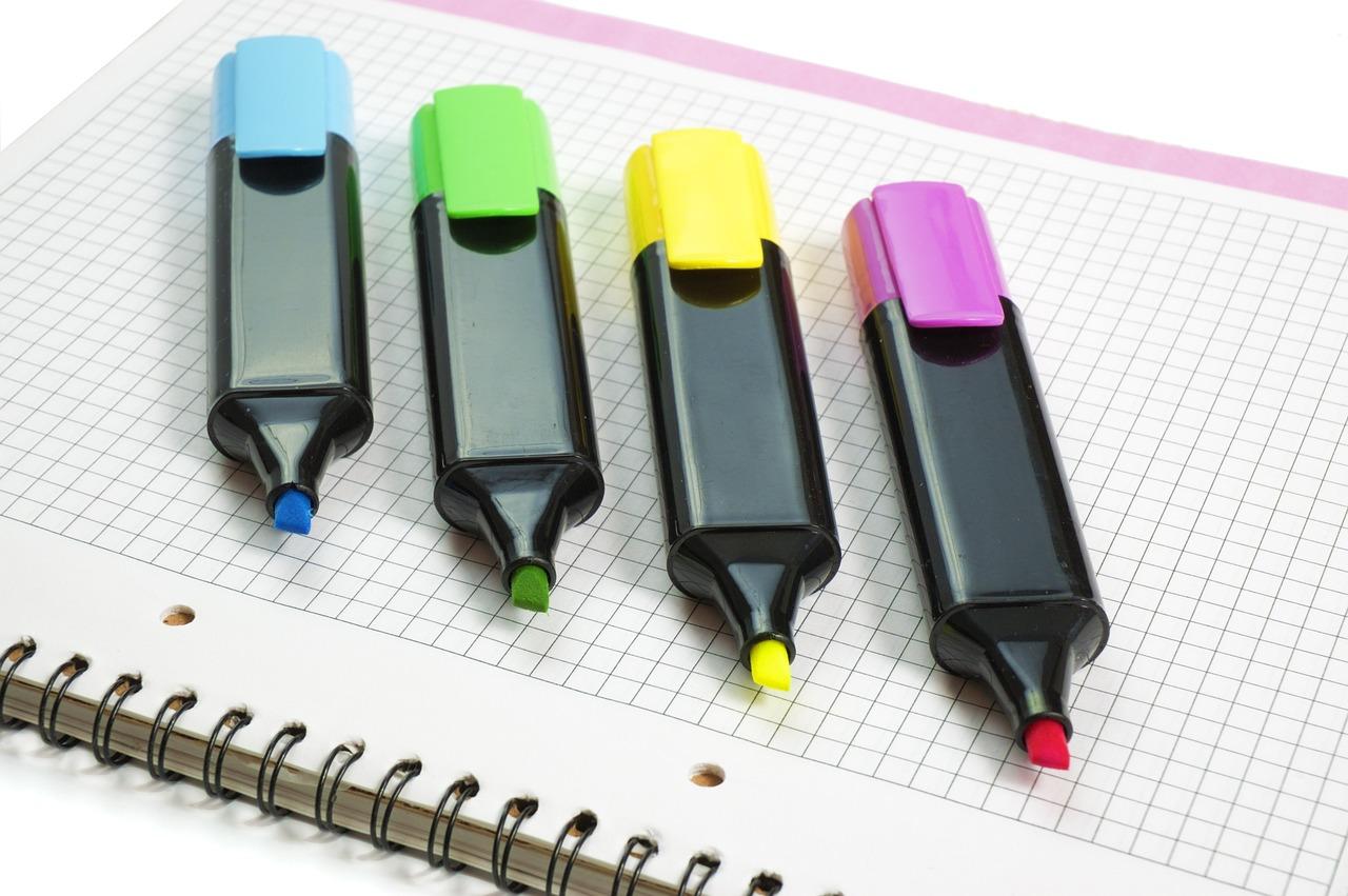 Set de rotuladores de colores brillantes sobre papel cuadriculado, representando los materiales de dibujo para niños