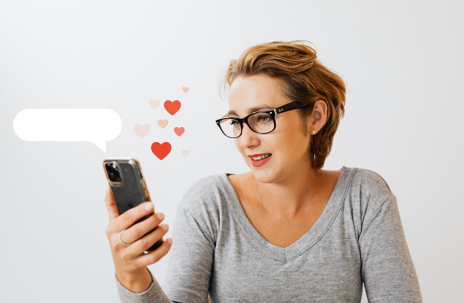 Persona utilizando un smartphone rodeada de símbolos de corazones digitales, ilustrando la comunicación emocional.