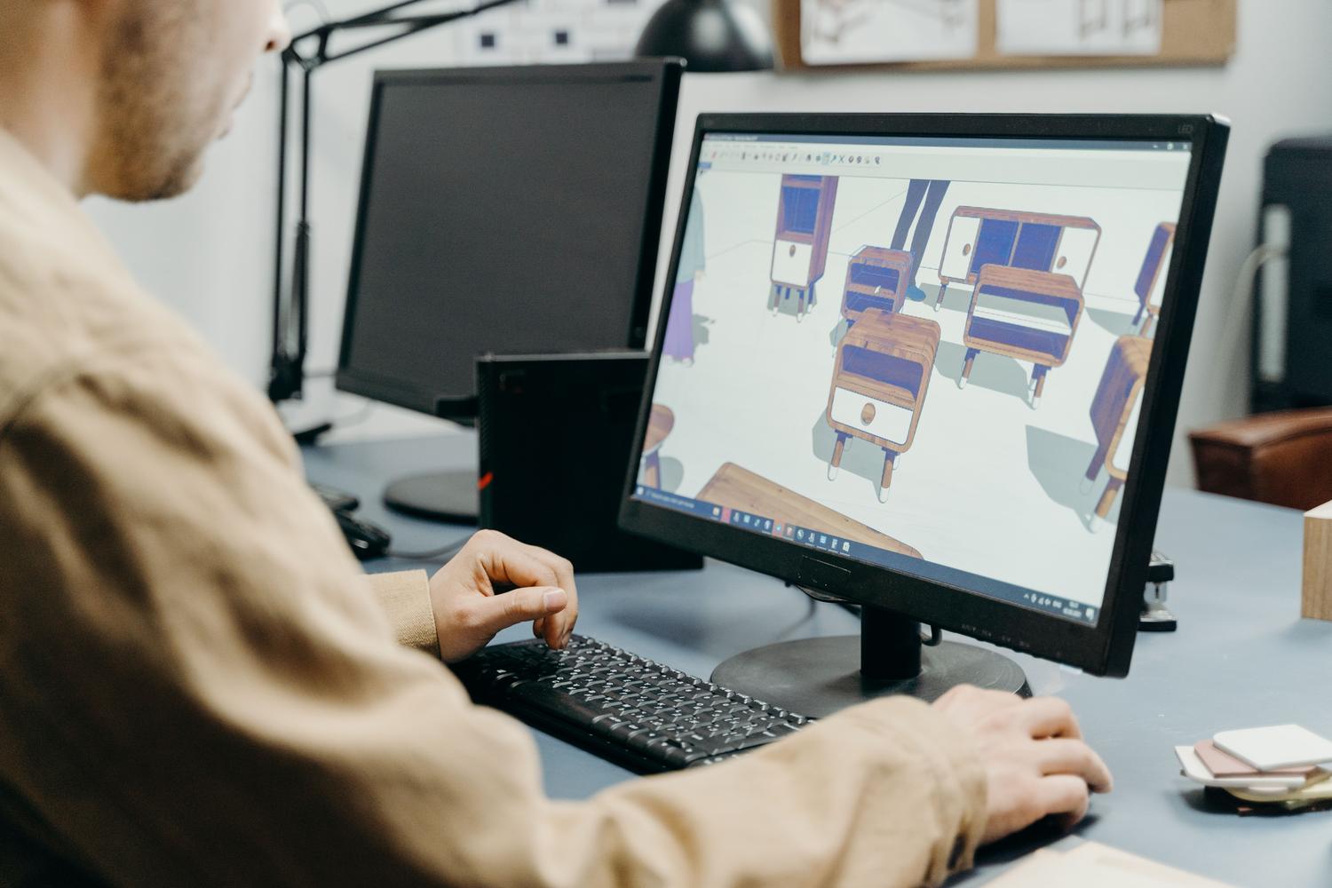 Diseñador trabajando en un ordenador con software de modelado 3D, representando el proceso creativo de los emojis Noto 3D.
