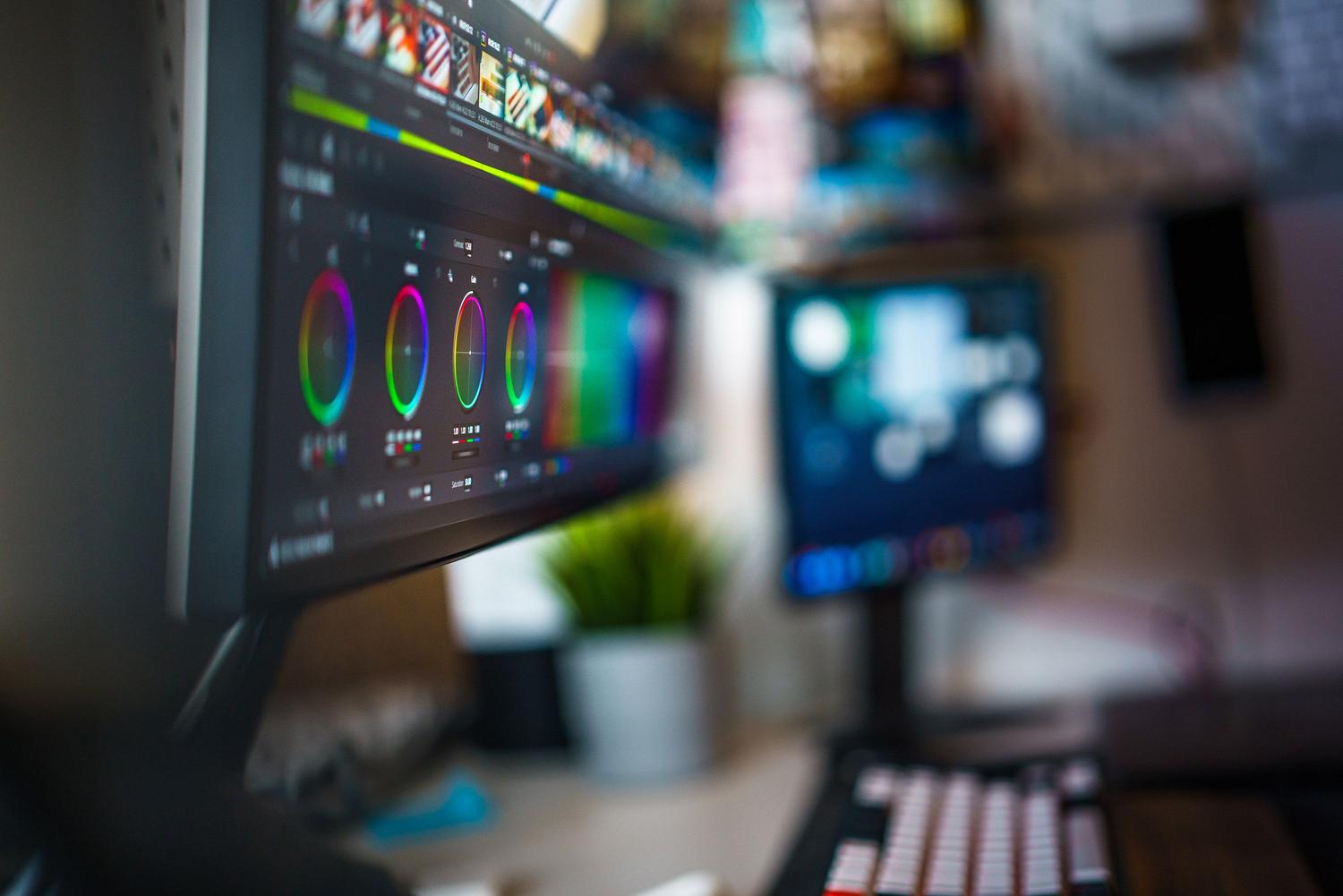 Estudio de edición de vídeo profesional con monitores de alta resolución mostrando herramientas de corrección de color en un entorno oscuro y sofisticado.