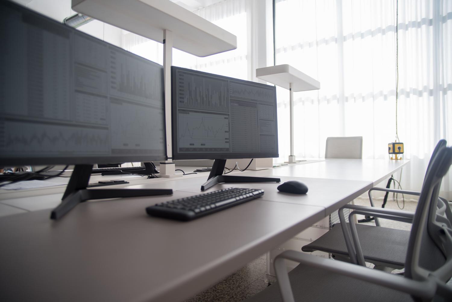 Entorno de oficina profesional con múltiples monitores utilizados para el análisis de datos, ideal para ilustrar la productividad y el espacio de trabajo extendido.