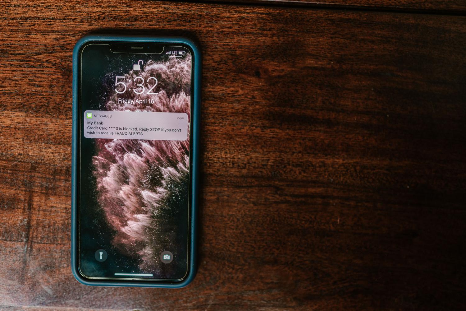 Primer plano de un smartphone con una notificación de alerta bancaria, ejemplificando la naturaleza instantánea y automática de los webhooks.