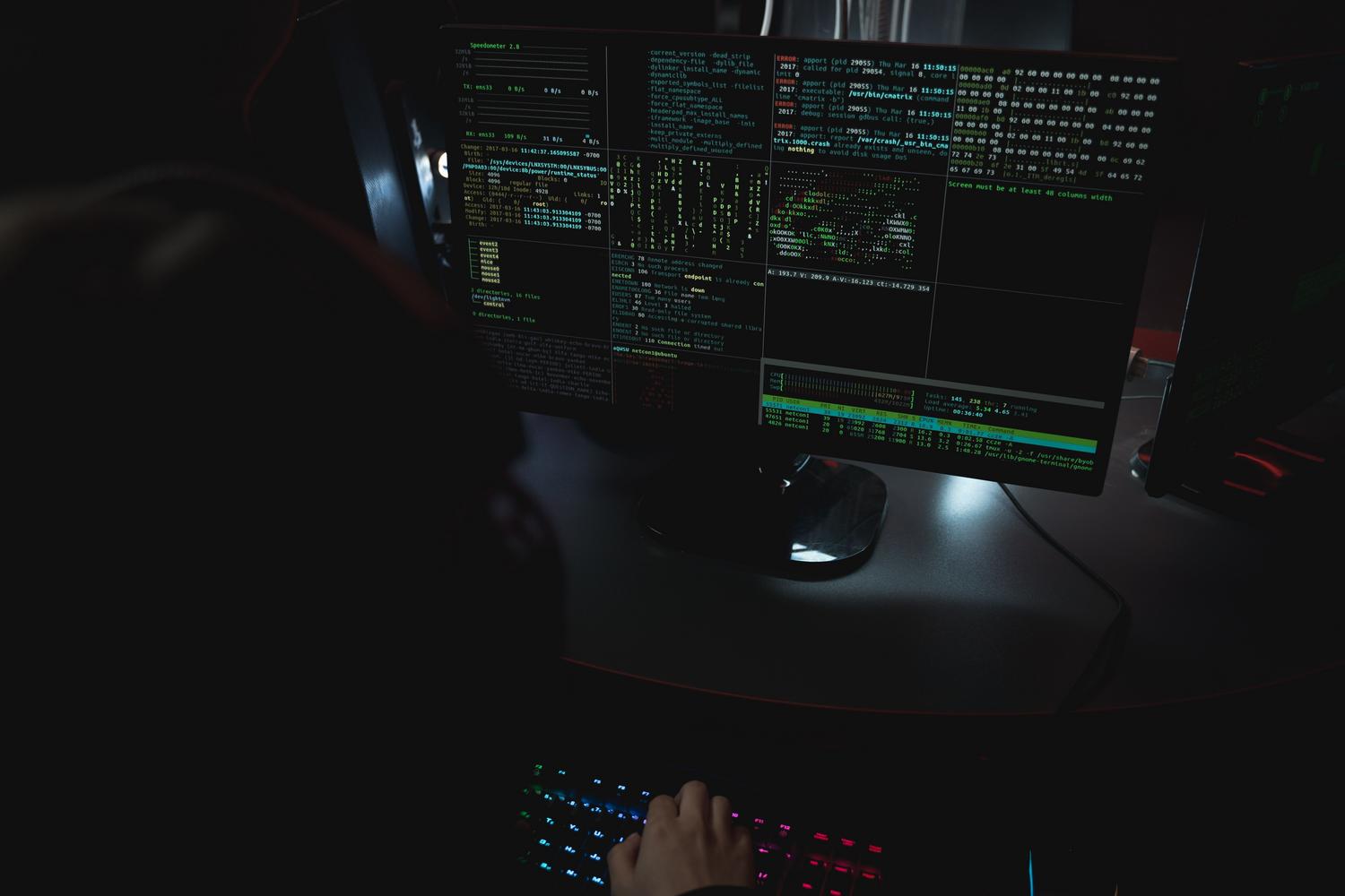 Entorno de trabajo oscuro con múltiples monitores mostrando líneas de comandos y terminales de hacking.
