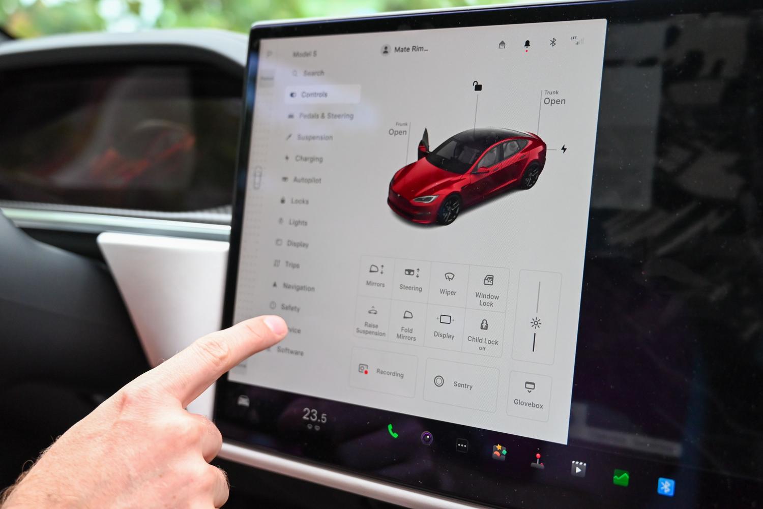 Mano interactuando con la pantalla táctil de un coche eléctrico, representando el control intuitivo y la gestión de aplicaciones.