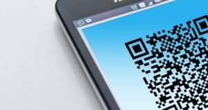 Primer plano de un smartphone mostrando un código QR en pantalla, ilustrando la conexión entre el mundo físico y digital.