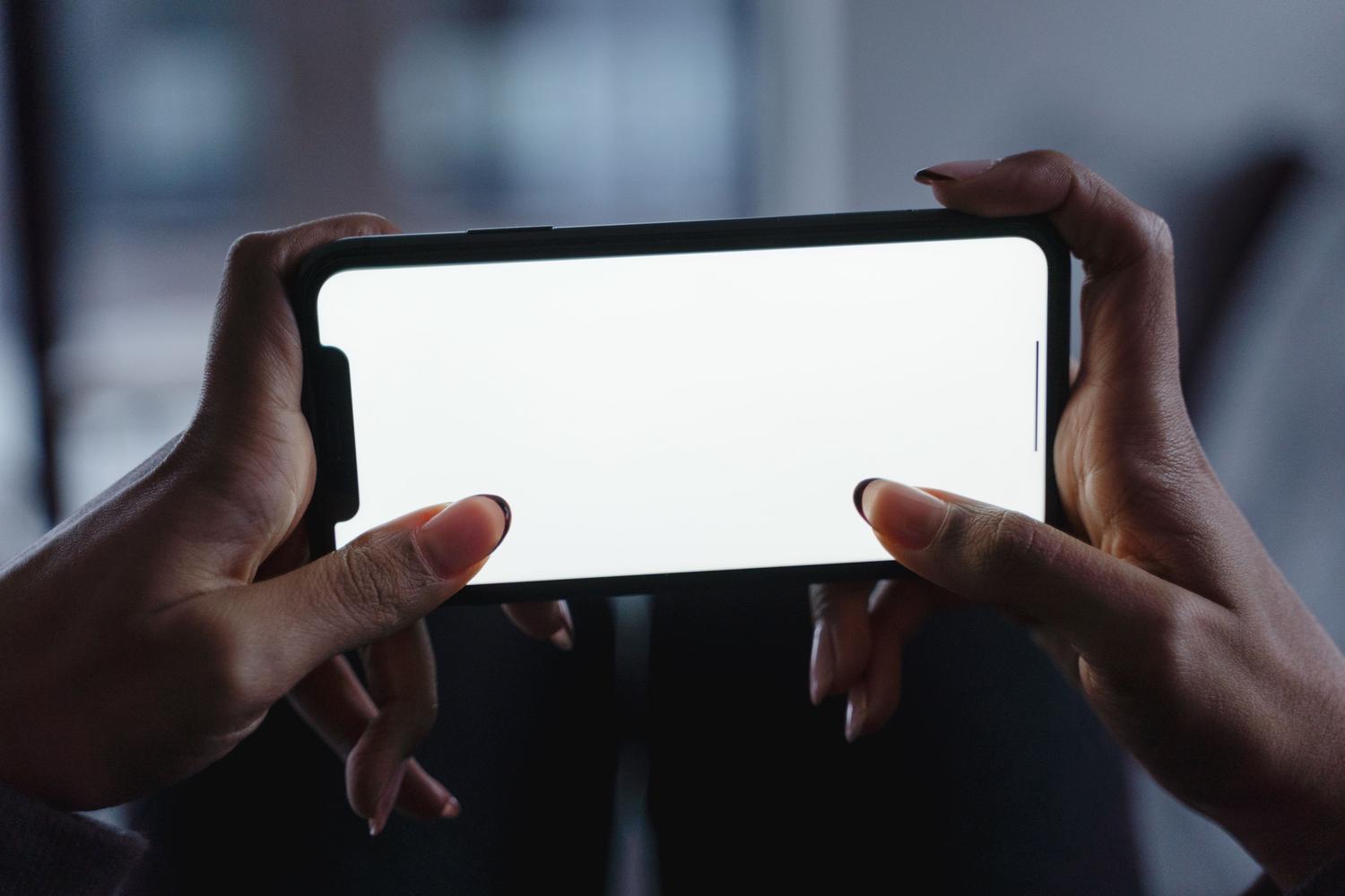Manos sosteniendo un smartphone con pantalla en blanco, ideal para representar el acceso al menú de ajustes.
