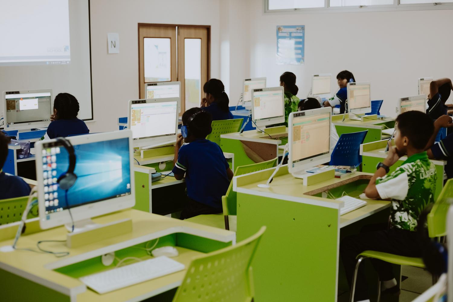 Niños aprendiendo en un laboratorio de informática moderno, ilustrando la integración de hipermedia y herramientas digitales.