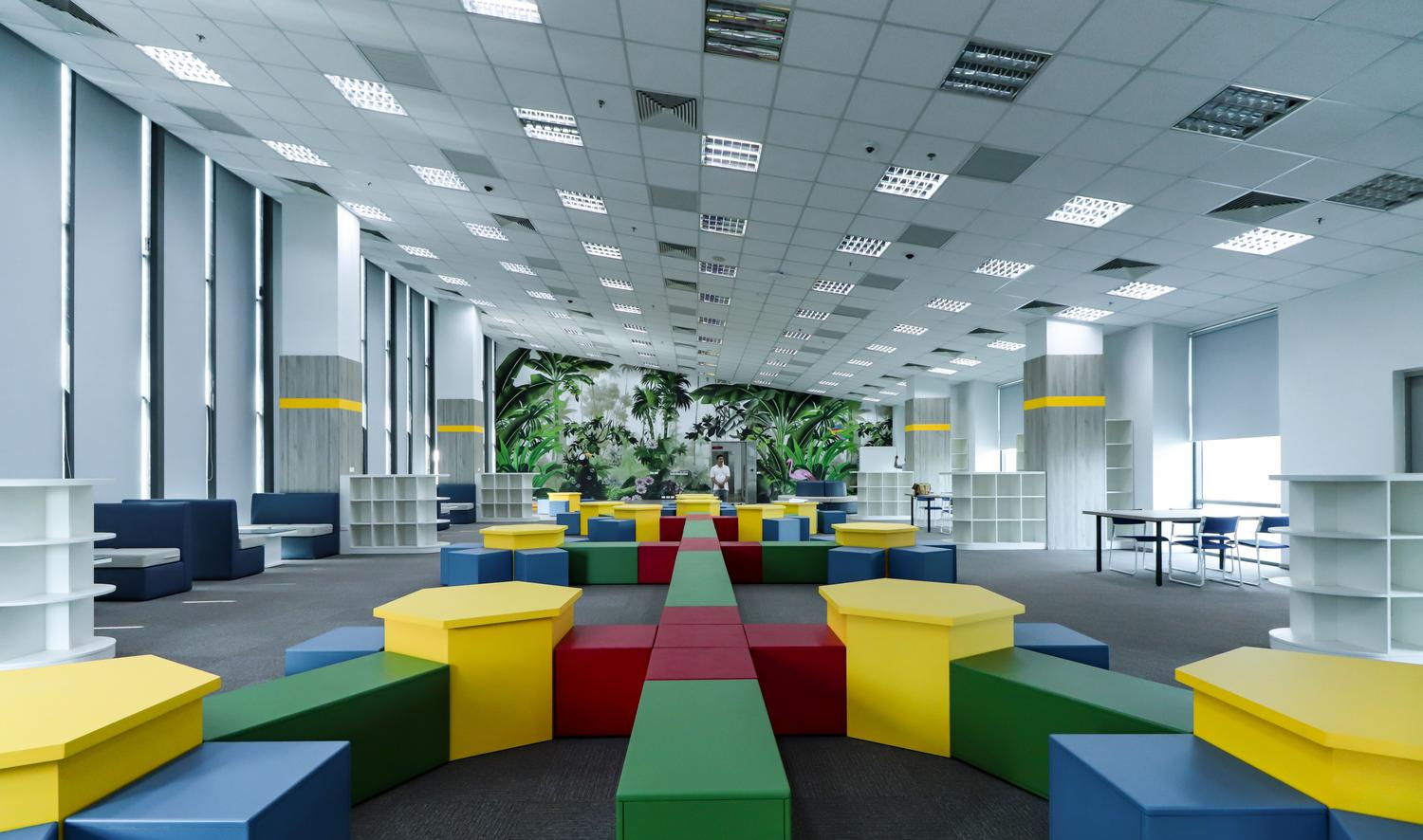 Espacio educativo moderno y flexible con mobiliario colorido, representando el concepto de hiperaula.