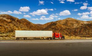 Camión semi rojo recorriendo una carretera desértica en Nevada, representando la atmósfera meditativa de American Truck Simulator.