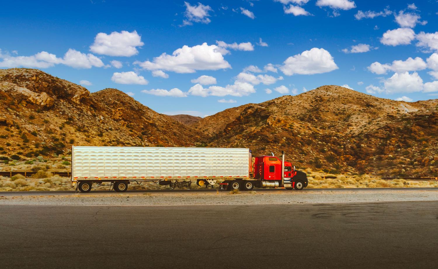 Camión semi rojo recorriendo una carretera desértica en Nevada, representando la atmósfera meditativa de American Truck Simulator.