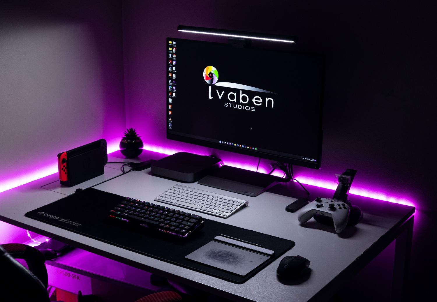 Setup de escritorio gaming moderno con iluminación LED púrpura y periféricos avanzados