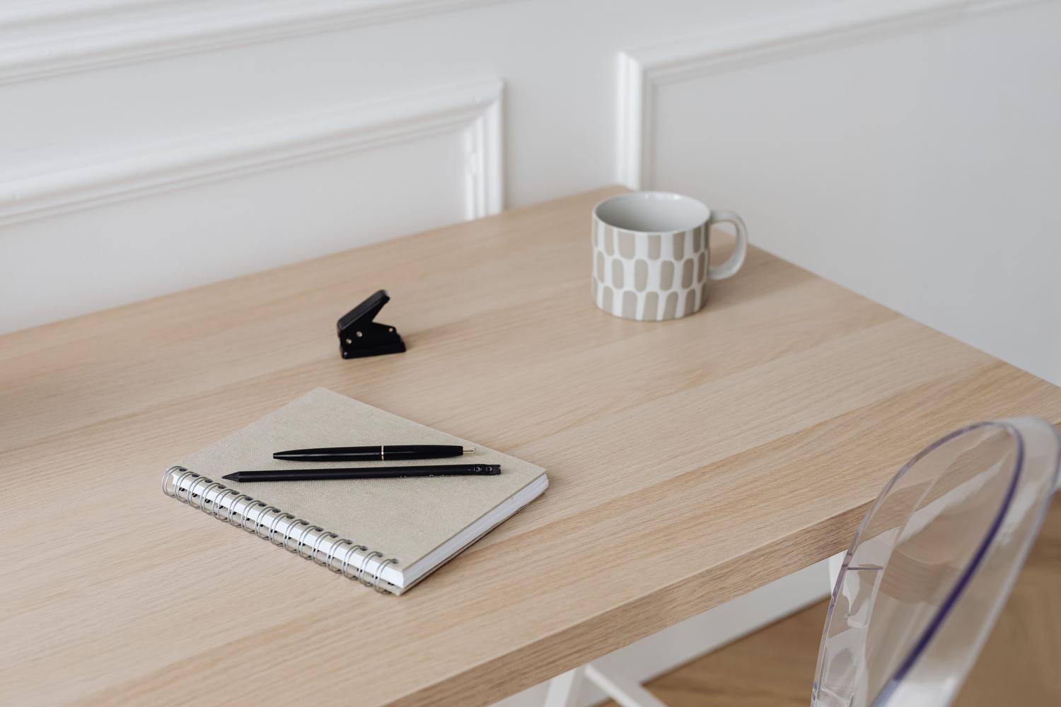 Detalle de mesa de escritorio de madera natural con cuaderno y material de oficina
