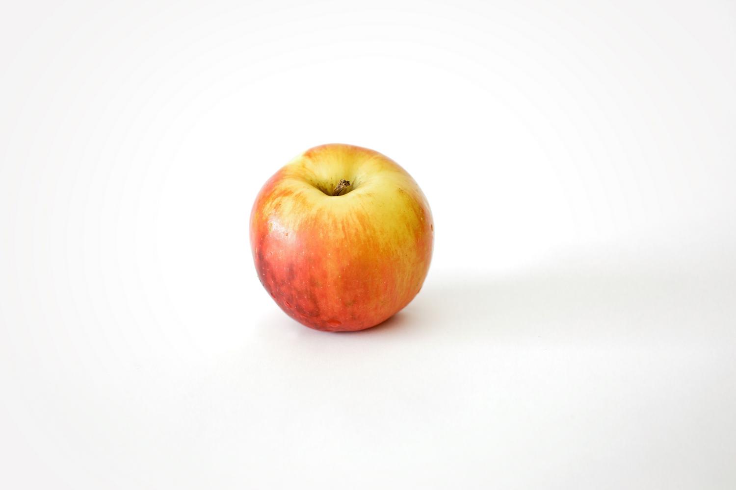 Una manzana roja vibrante sobre un fondo blanco, ejemplo visual de una palabra grave sin tilde.