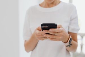 Persona sosteniendo un iPhone en un entorno luminoso y minimalista, ideal como imagen de portada para un tutorial tecnológico.