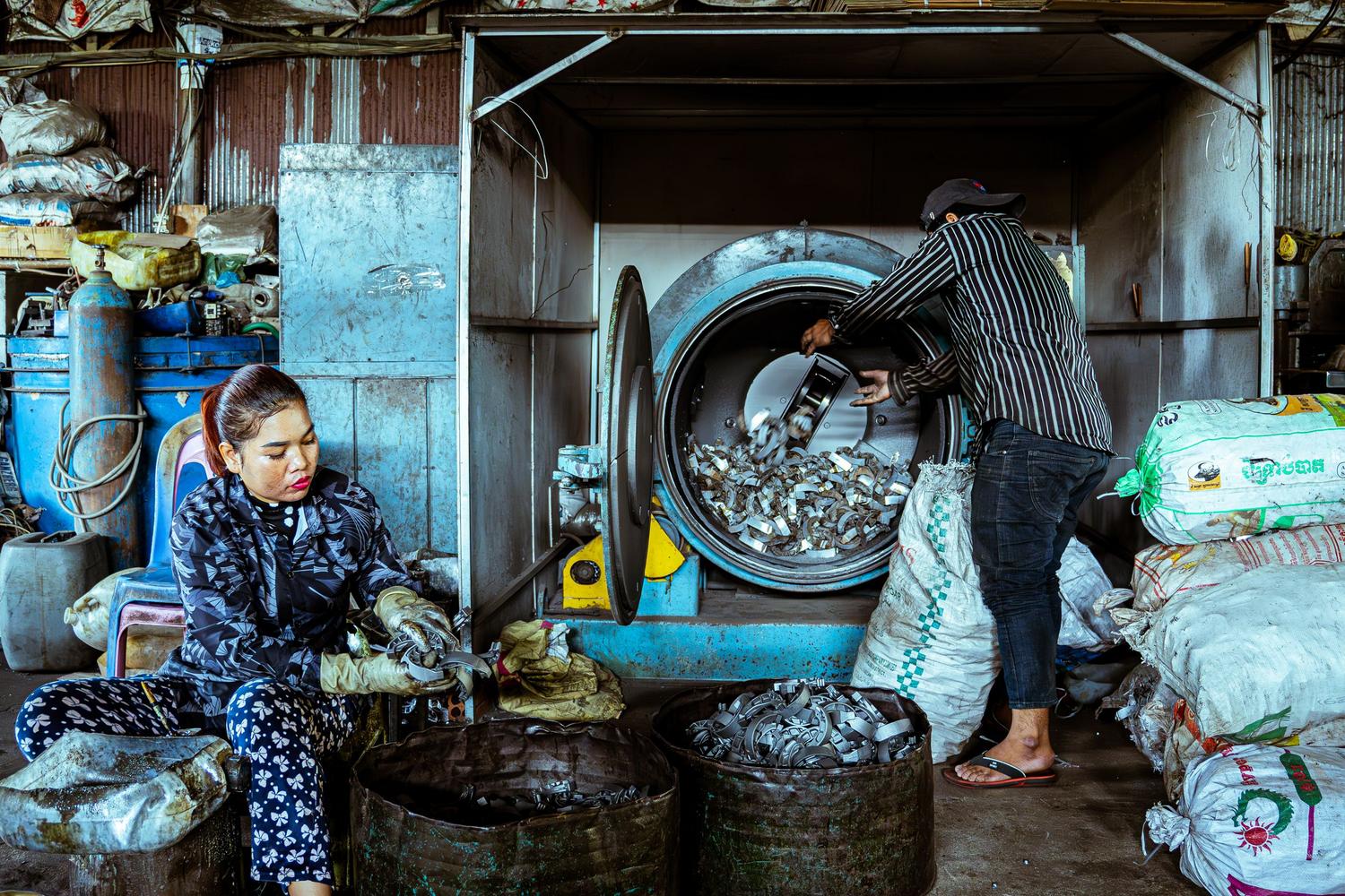 Trabajadores clasificando metales en una planta de reciclaje, representando la economía circular y la gestión de residuos.