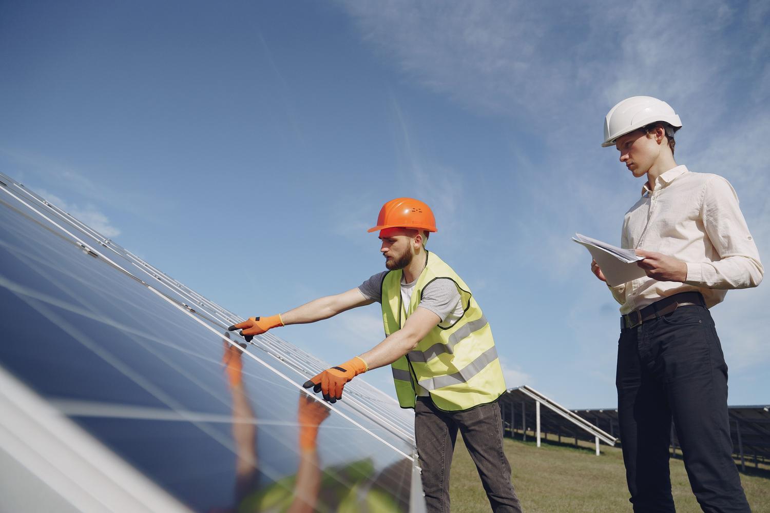 Técnicos especializados inspeccionando paneles solares en una planta de energía fotovoltaica, representando los empleos técnicos en energías renovables.