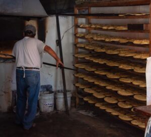 Panadero tradicional preparando hogazas de pan artesanal en una panadería rústica, ilustrando el ejemplo del valor intangible de un negocio local.