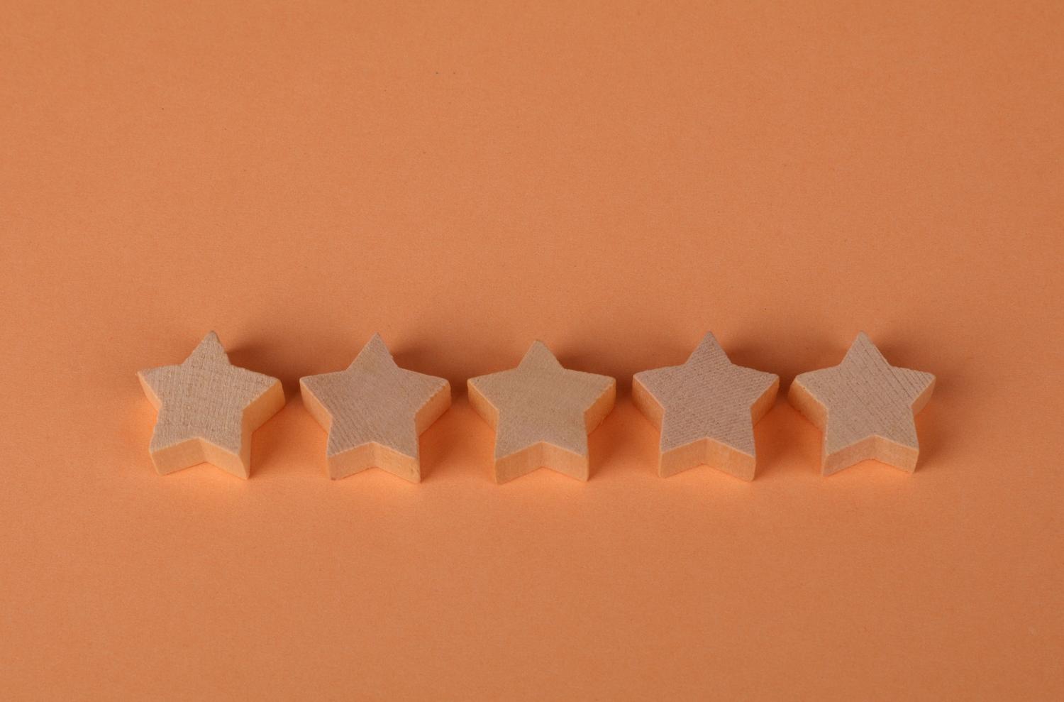 Cinco estrellas de madera sobre un fondo naranja, representando la reputación y el prestigio de una marca.