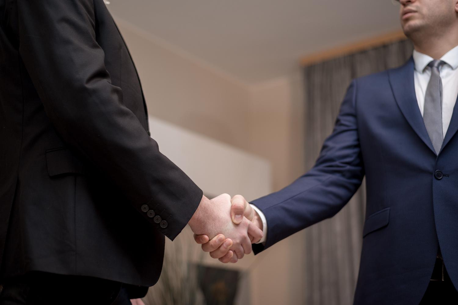 Dos empresarios dándose la mano en un entorno profesional, simbolizando la adquisición de una empresa y el acuerdo sobre el fondo de comercio.