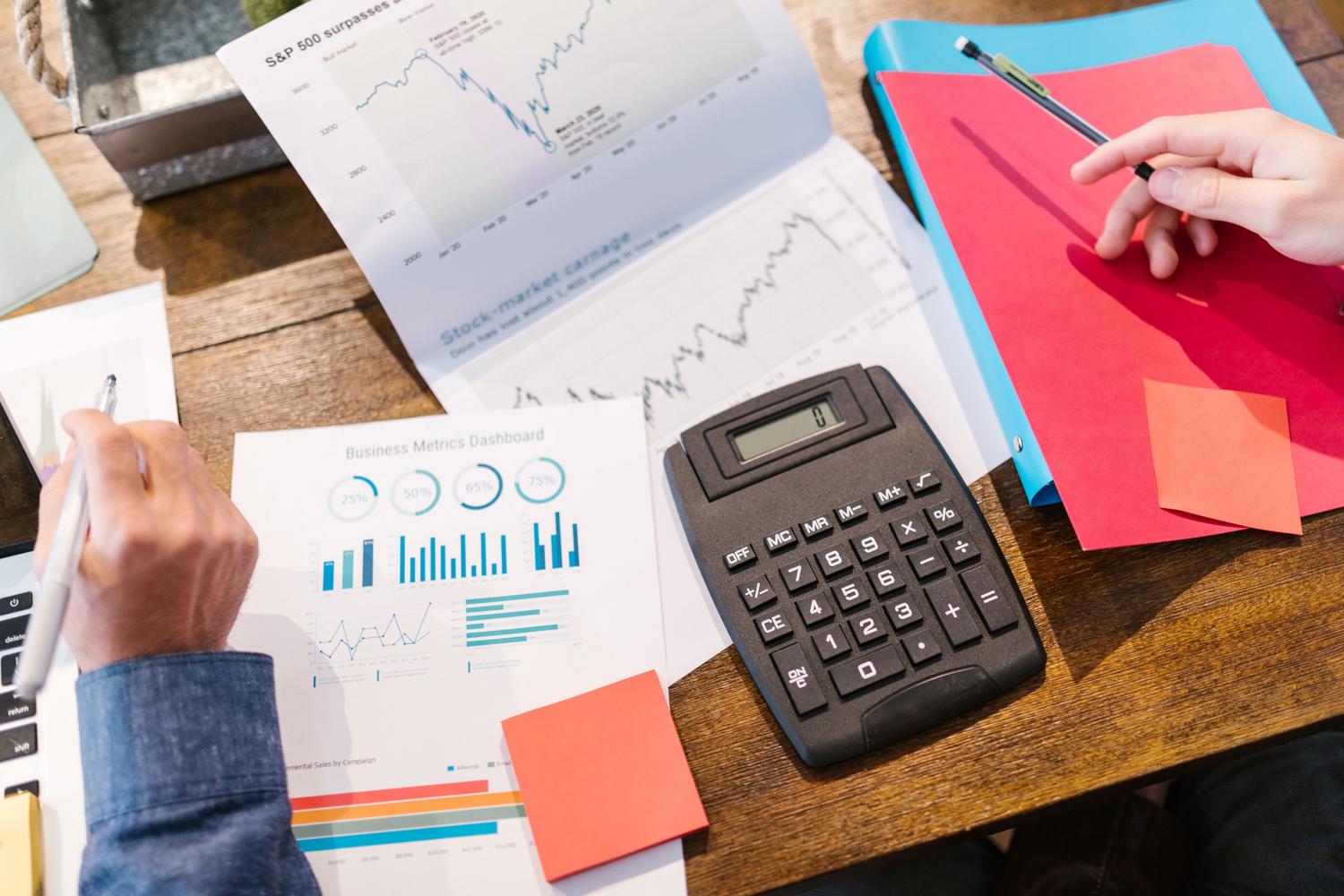 Herramientas de análisis y planificación financiera con gráficos y calculadora sobre un escritorio de madera.