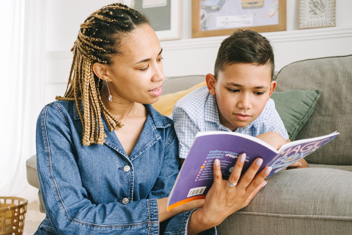 Madre leyendo un libro junto a su hijo en el sofá, simbolizando el pilar emocional y el apoyo familiar necesario para superar la dislexia