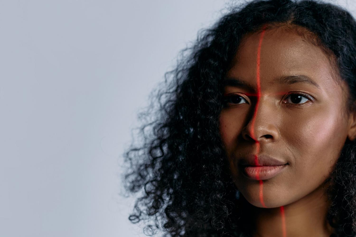 Primer plano de una mujer siendo escaneada con un láser facial, representando el proceso de captura de datos biométricos para crear deepfakes.