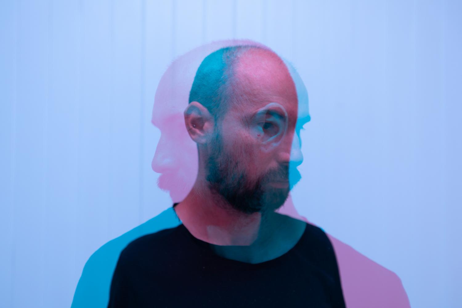 Retrato de un hombre detrás de un cristal con reflejos, evocando la neutralidad afectiva y la barrera emocional con el mundo.