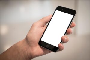 Persona sosteniendo un smartphone moderno con pantalla blanca, representando la interfaz de un sistema operativo.