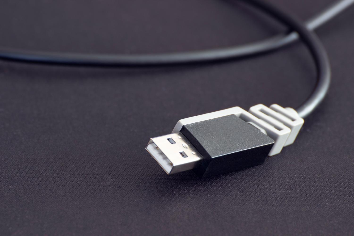 Primer plano detallado de un cable USB negro sobre un fondo oscuro, destacando la importancia de usar un cable de calidad para la detección del dispositivo.