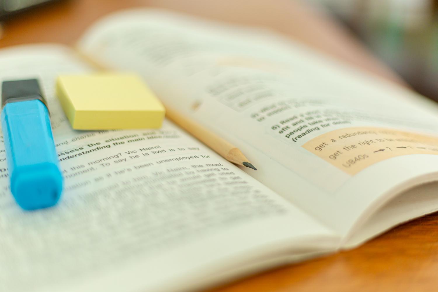 Libro de gramática abierto con resaltador y notas adhesivas, representando el análisis y la organización del estudio lingüístico.