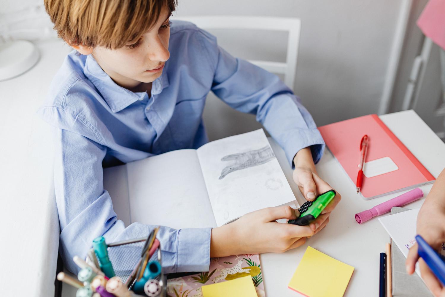 Niño de primaria concentrado utilizando una calculadora verde mientras estudia matemáticas.